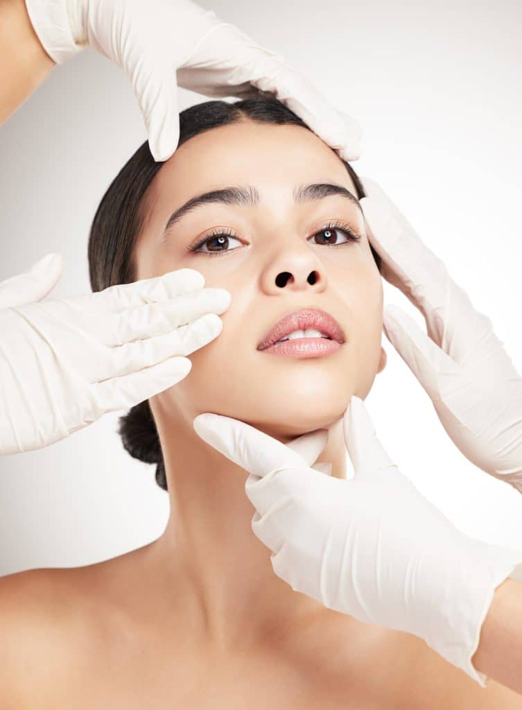 Portrait of a young mixed race woman having her face examined against a grey studio background. His